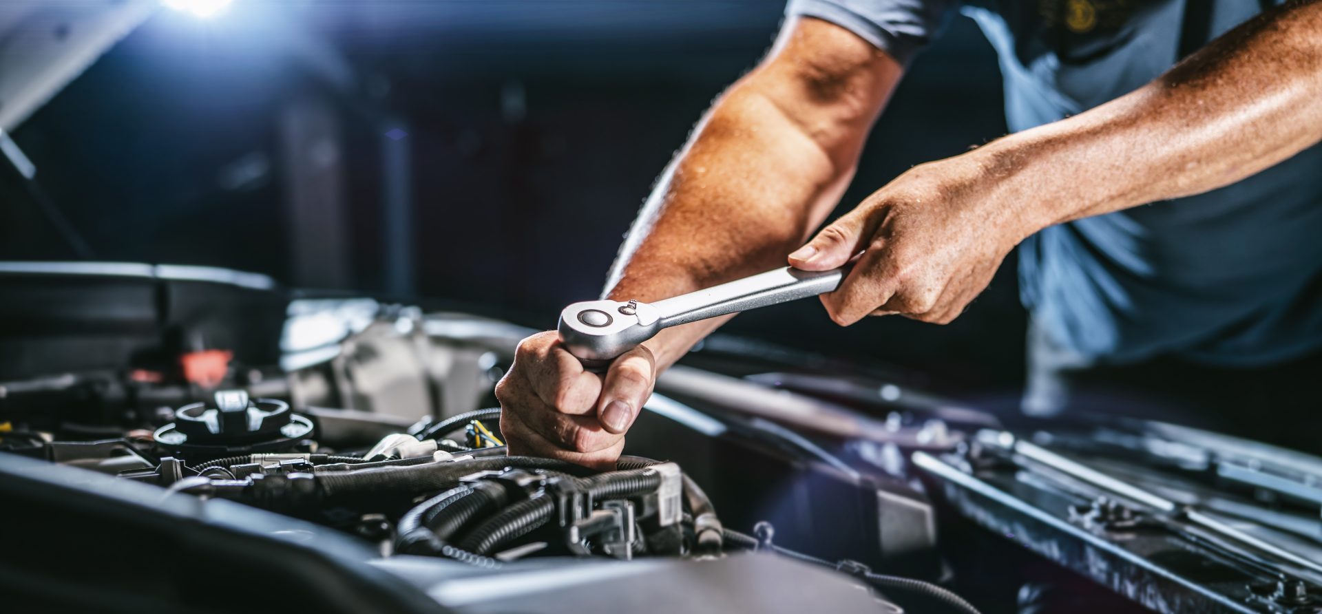 Man repairing a bmw engine with a wrench 